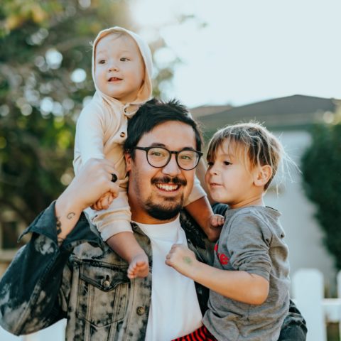 man in white shirt carrying girl in gray shirt